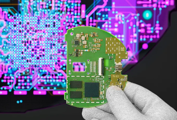 Cicor engineer holding a PCB in front of a screen displaying the PCB design