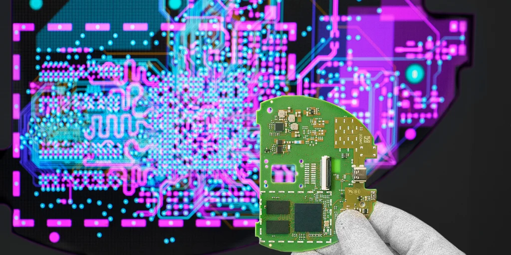 Cicor engineer holding a PCB in front of a screen displaying the PCB design