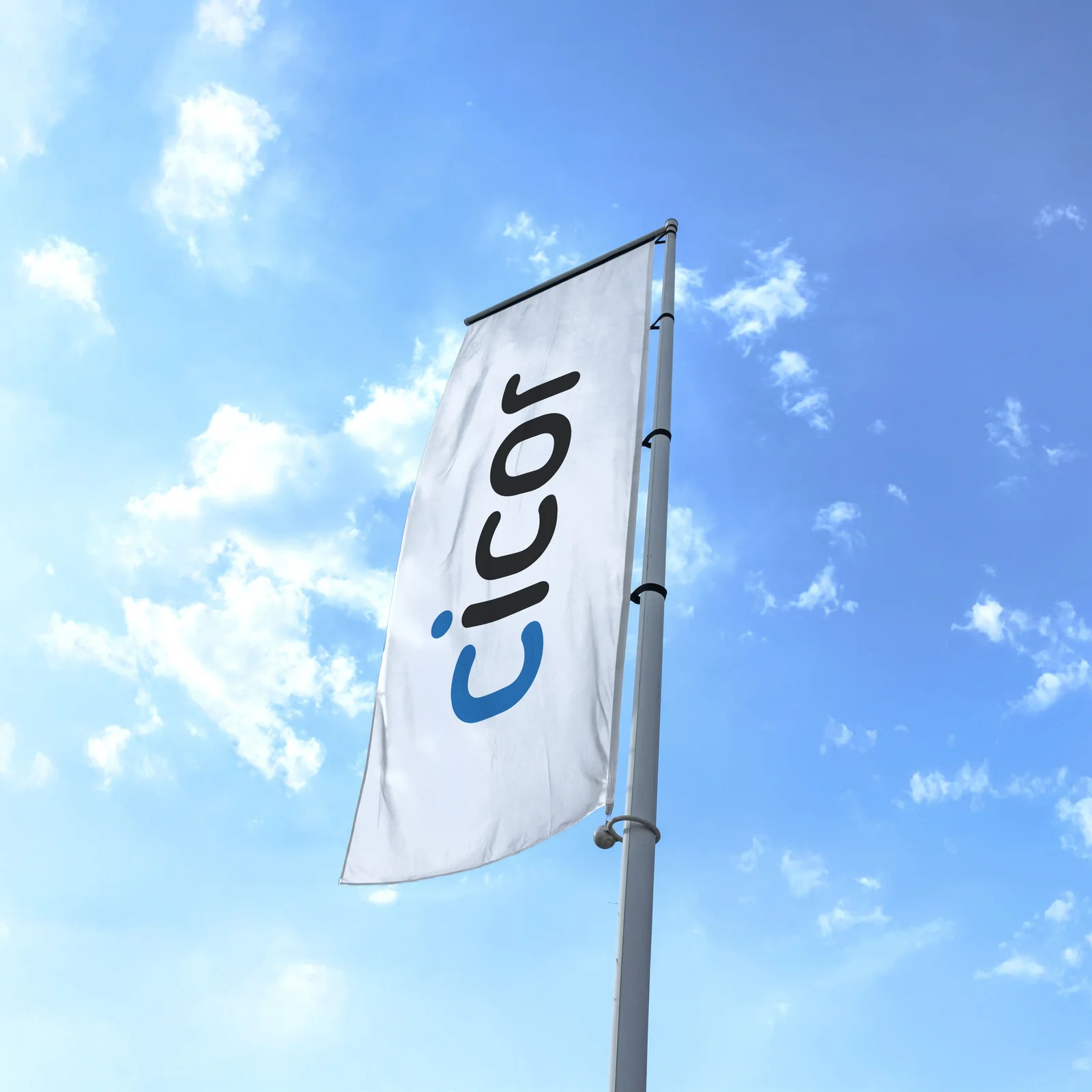 Cicor corporate flag flying against a blue sky with white clouds.