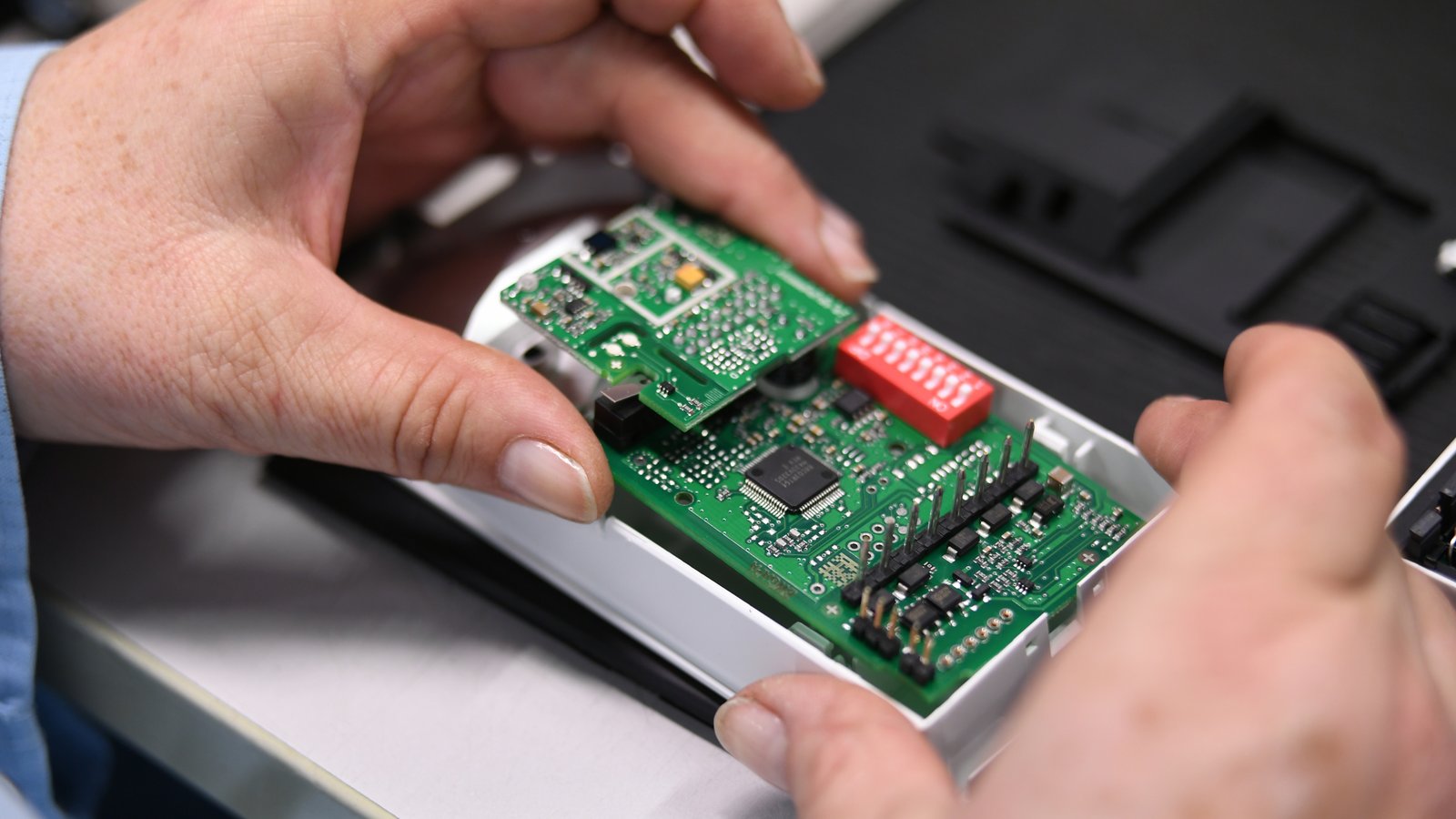 Close-up of a Cicor employee integrating a PCB into a housing (box building)