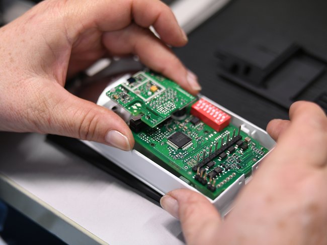 Close-up of a Cicor employee integrating a PCB into a housing (box building)